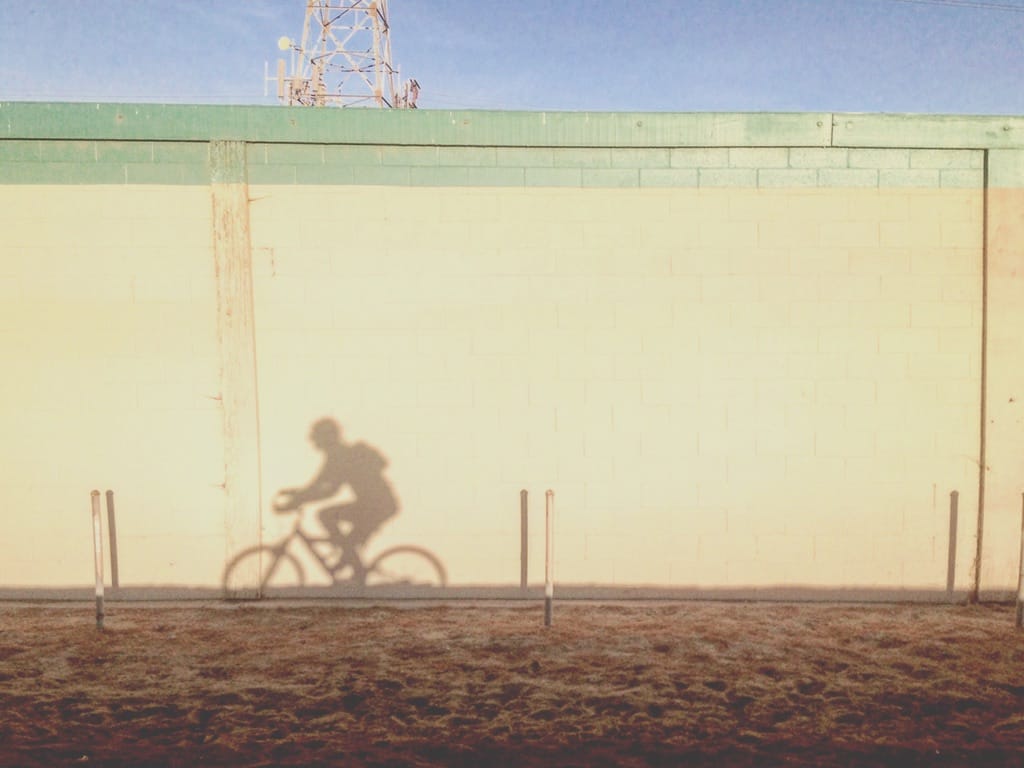 1E288B49-0F4E-4036-9C3E-1EF5894ECCBA_1_105_c Shadow of bike rider on yellow wall.